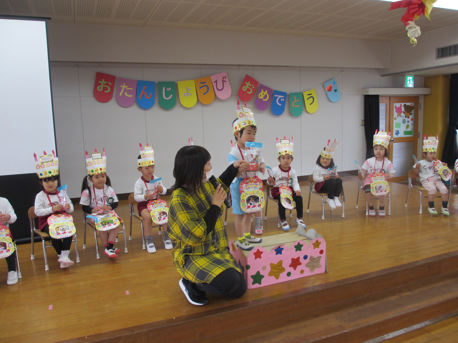 先生から誕生日プレートや、冠の紹介をしてもらいました。「みんなも、誕生日になったらもらえるから楽しみに待っていようね！」の先生の言葉に安心する子どもたちでした。